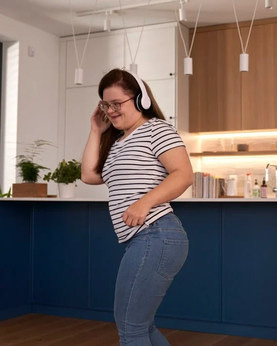 Disabled woman with down syndrome smiling while dancing to music in the kitchen