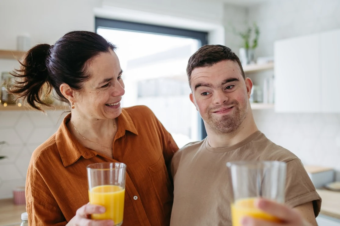 Disabled man with down syndrome in kitchen smiling with support worker